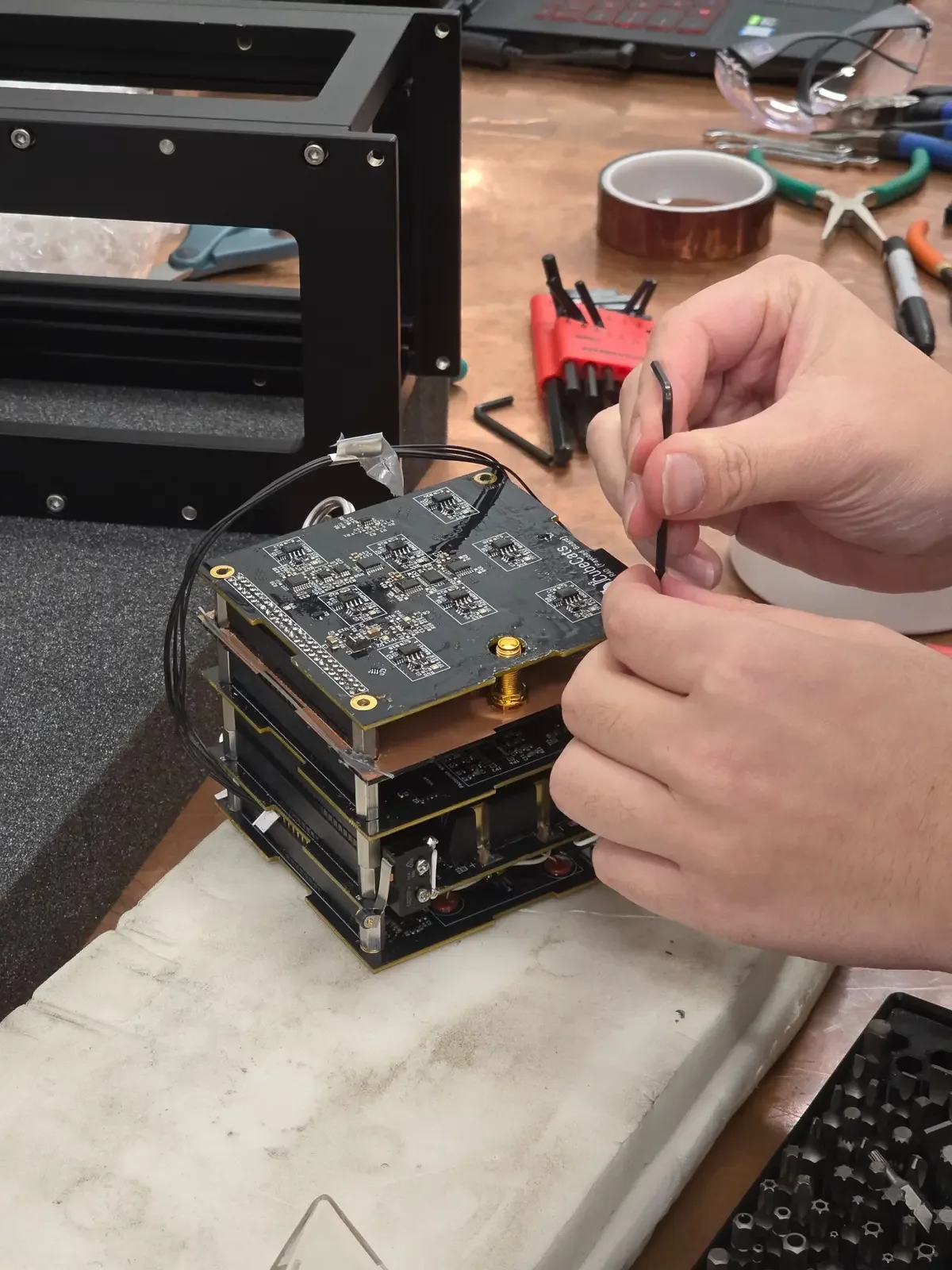 Hands assembling a UC CubeCats satellite electronics stack